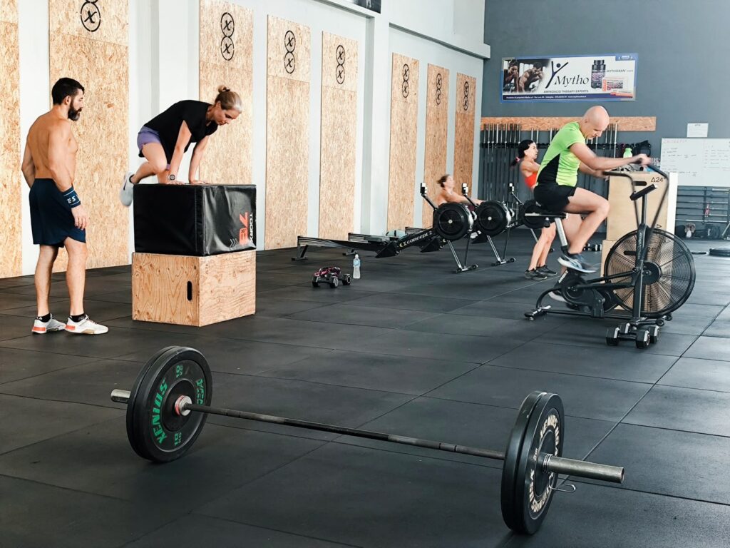 Gruppo in allenamento di cross training tra box jump, vogatori e assault bike
